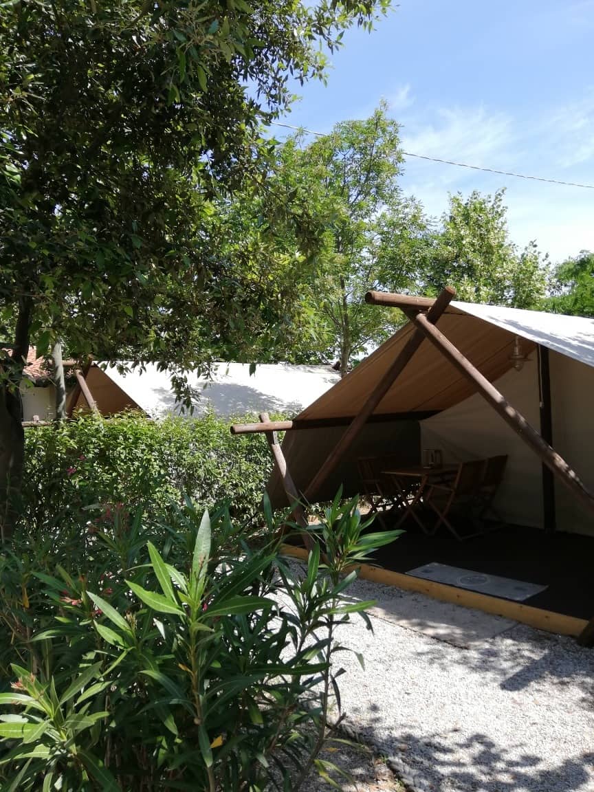 Due tende lodge tra siepi e vegetazione