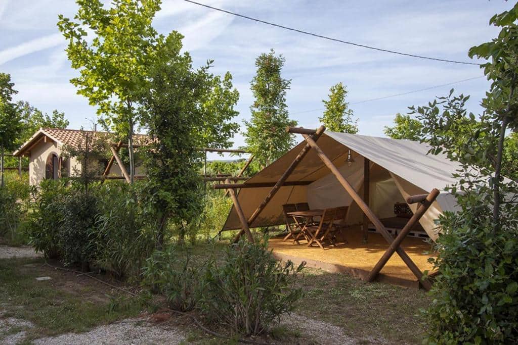 Lodge glamping con tavolo in veranda tra alberi e verde